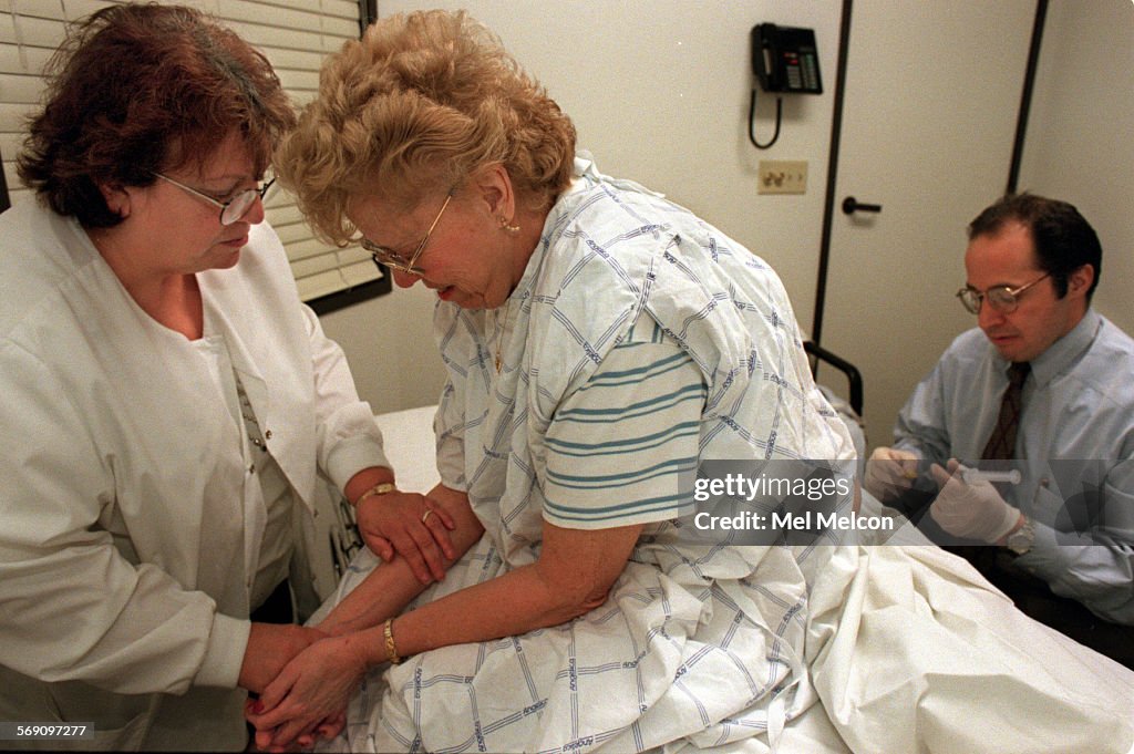 R.N. Pat Roth comforts patient Helena Durocher as she prepares to receive trigger point injections f