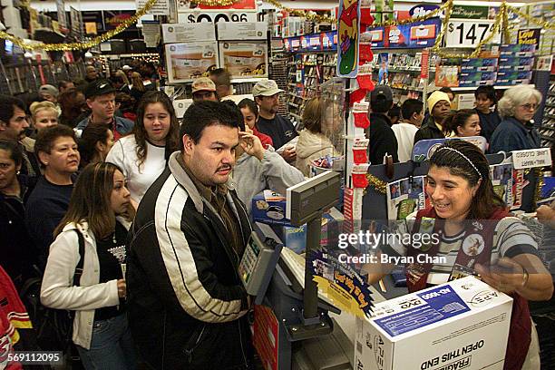Cesar Rodriguez, left, buys a Nintendo Gameboy from WalMart associate Sofie Castillo as others wait to do the same Friday in Oxnard. People lined up...