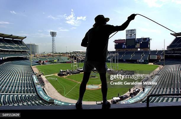 Tom Colley,, of Riverside, a Harvest Crusade volunteer since its inception, pulls sound cable up and around stadium seating to connect audio for...