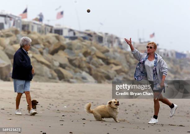 Lisa Elward, right, tosses a ball to her dog Schatzi while walking with friend Ruthie Bitting along Rincon Beach north of Ventura Thursday. They were...