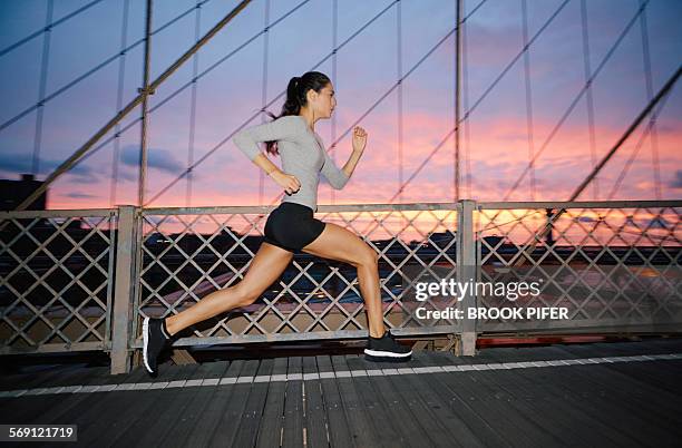 young woman running early morning in urban setting - short de cycliste photos et images de collection