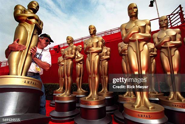 Oscar1.rm Mark RossSullivan carries a fiberglass Oscar statue. Several hundred people were striking the set at the Shrine Auditorium this morning.