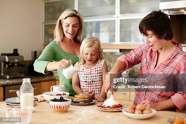 a same-sex couple is cooking with their kid. - making pancakes stock pictures, royalty-free photos & images