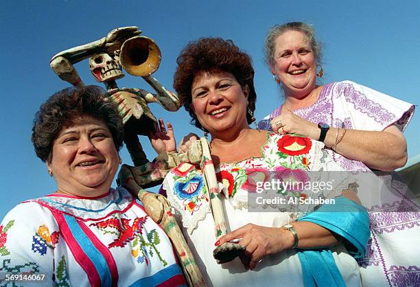 Amigas de la Cultura from left: Sylvia Krenzien, Teri Rocco, and Alice Rumbaugh, holding Dia de los Muertos wooden skeleton, have joined together to...