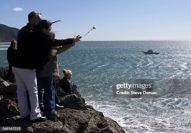 Columba Chavez Garcia, left, and her niece Candy Chavez throw a flower into the Pacific Ocean at Pt. Mugu during a stone dedication ceremony...