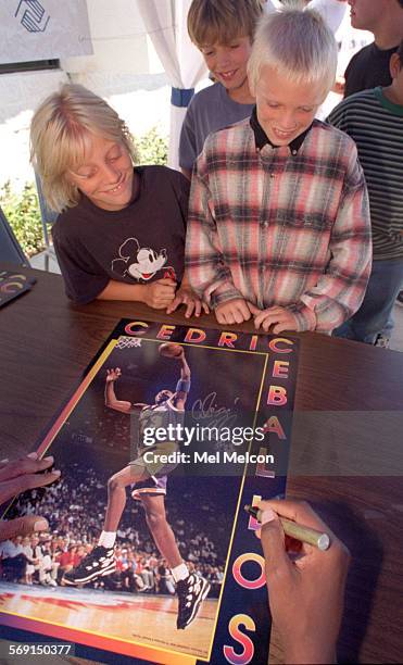 Lisa Anderson and her brother Nate look on as Cedric Ceballos of the Los Angeles Lakers autographs a poster of himself while at Jano Graphics in...