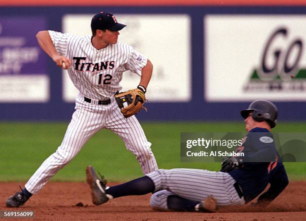 Cal State Fullerton shortstop Mike Martinez, left, tags up at second base to out alumni player Jake Epstein, right, while attempting a double play...
