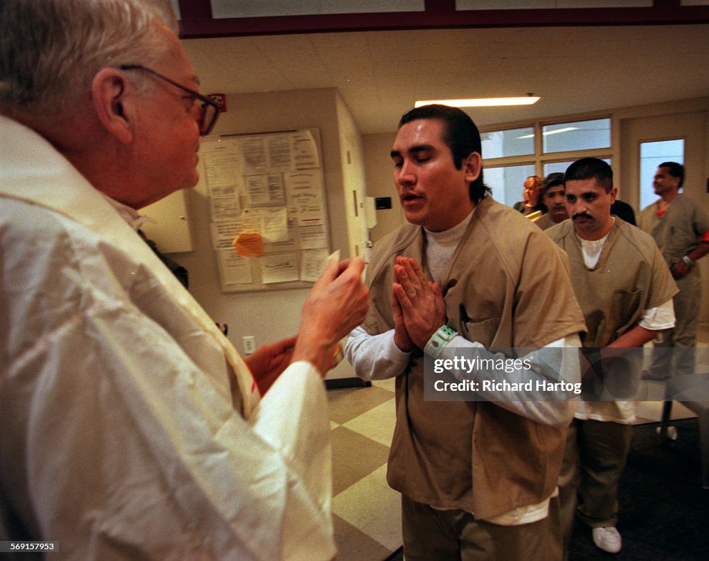Prisoners line up to receive communion from Father Brendan Smith, left, after mass at the Santa Ana