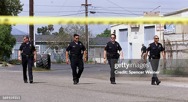 Oxnard Police officer walk along Balboa Street at investigation site of homicide Monday in El Rio.