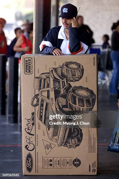 Jose Barragan of Arleta waits for a ride with his son's Christmas present at the Panorama City Mall WalMart on Friday morning. DIGITAL IMAGE SHOT ON...