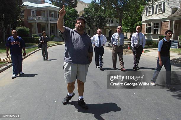 Warner Brothers Studio tour guide Dean Ricca foreground, points out things to see as he and a group of tourists walk down an area called Midwest...