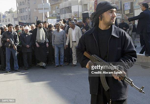An Iraqi Shiite man provides security as others take part in a protest against the bombing of a Shiite holy shrine on February 23, 2006 in the...