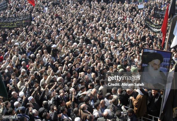 Iraqi Shiite men chant slogans as a picture of Iraq's powerful Shiite cleric Grand Ayatollah Ali al-Sistani is seen during a protest against the...