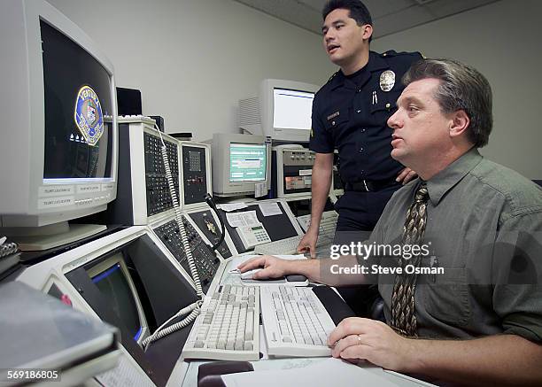 Corporal Ralph Martinez, left, is assisted by Pat Cronan with the computer networking system in the dispatch center for the Ventura police and fire...