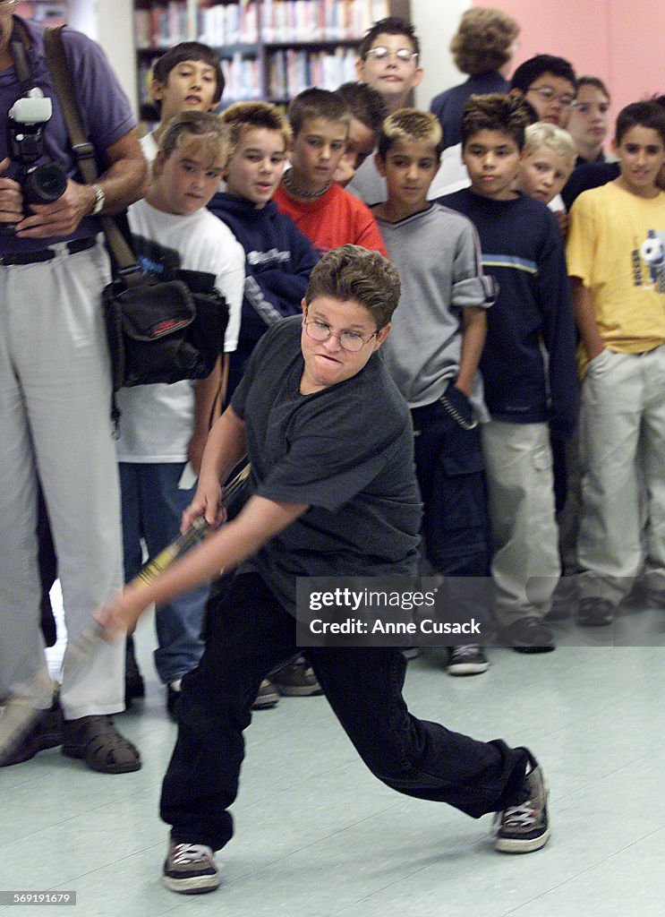 Fifth grader Brett Dagg takes a turn shooting a ball with a hockey stick toward a goalie as Luc Robi