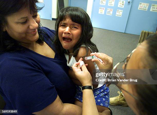 Laura Lopez holds her sixyearold daughter Julie Marquez as feels the needle from a Hepatitis A vaccine administered by nurse Silva Sandhu, right,...