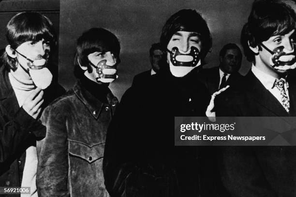 From left, George Harrison , Ringo Starr, John Lennon , and Paul McCartney of the British pop group the Beatles, walk in single file, all wearing fog...