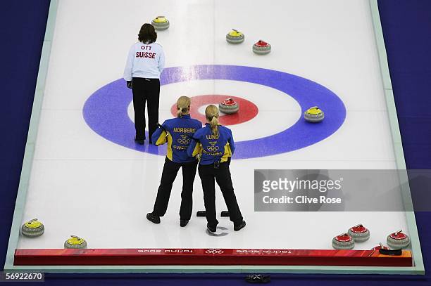 Eva Lund and Anette Norberg of Sweden look on as Mirjam Ott of Swtzerland lines up a shot during the gold medal match of the women's curling between...