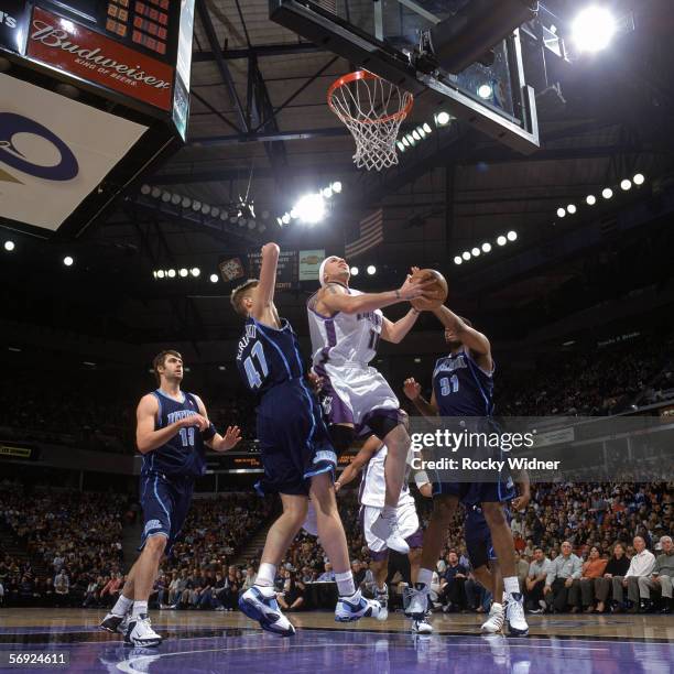 Mike Bibby of the Sacramento Kings goes up for a shot between Andrei Kirilenko and Jarron Collins of the Utah Jazz during a game at Arco Arena on...