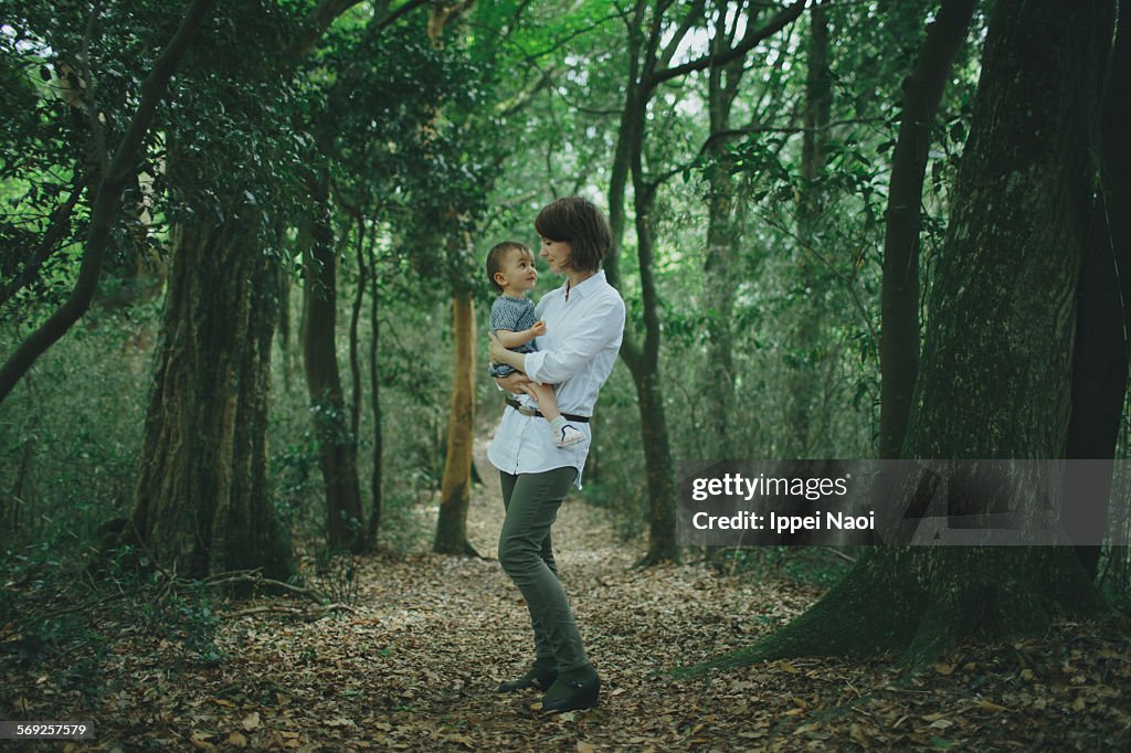 Mother and baby looking at each other in forest