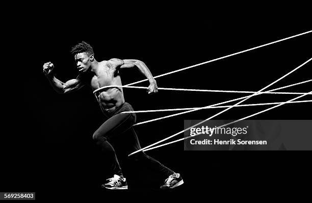 male athlete being hold back by ropes - male athlete with rope on black background stock pictures, royalty-free photos & images