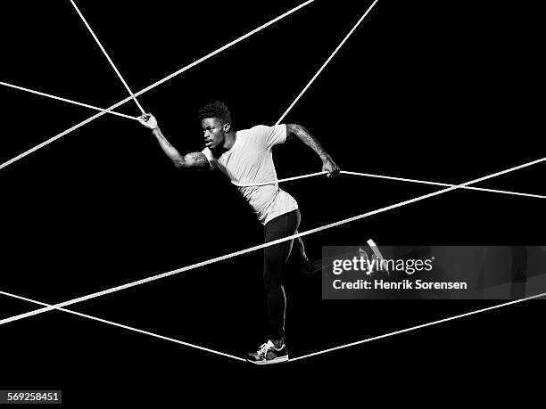 male athlete balancing on ropes - restraining photos et images de collection