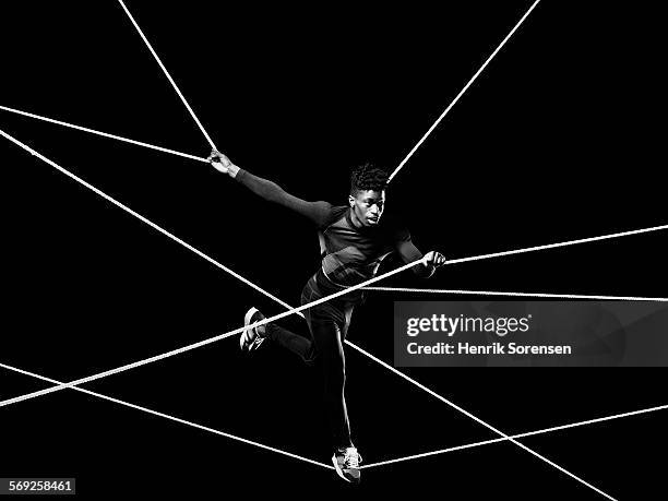 male athlete blancing on ropes - restraining photos et images de collection