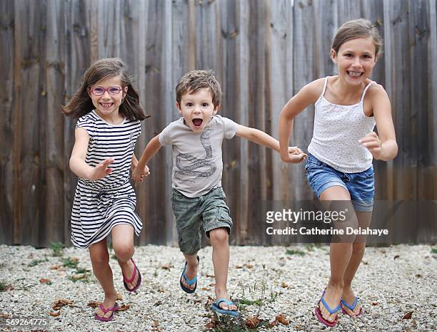 3 children posing together - girls wearing sandals stock-fotos und bilder