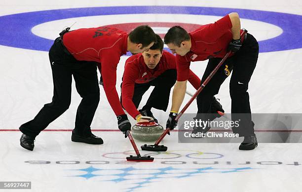 Pete Fenson of United States releases the stone as Shawn Rojeski and Joe Polo of United States brush the ice during the Gold medal match of the men's...