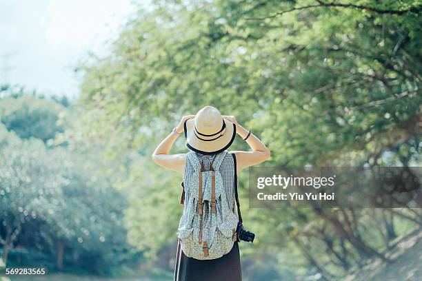 woman with sunhat standing against green nature - chapeau de paille photos et images de collection