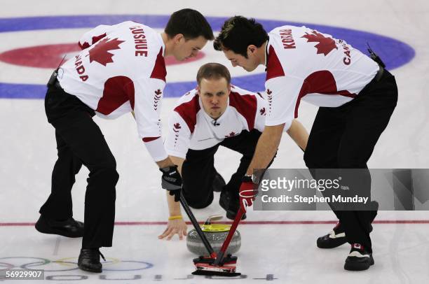 Mark Nichols of Canada releases a stone as Brad Gushue and Jamie Korab of Canada brush the ice during the Gold medal match of the men's curling...