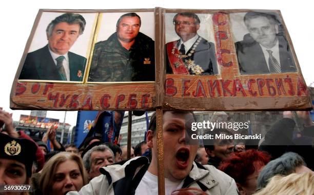 Serbian Radical party supporter holds photos of war crimes suspects Radovan Karadzic , Ratko Mladic and Vojislav Seselj at a rally in Belgrade...