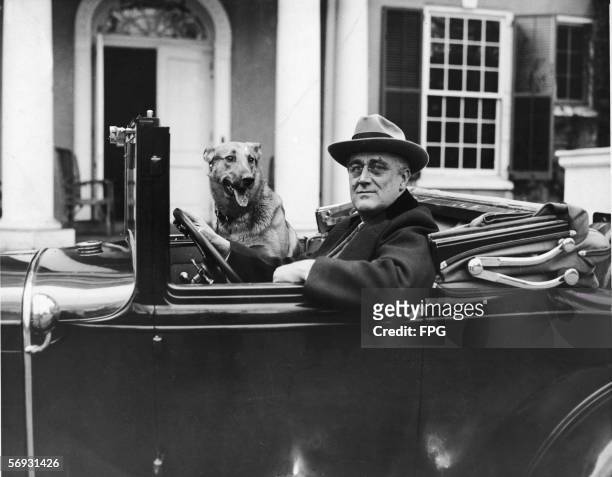 Portrait of American President Franklin Delano Roosevelt as he sits behind the wheel of his car outside of his home in Hyde Park, New York, mid 1930s.
