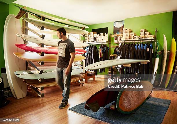 customer peruses boards at a maine surf shop. - sports equipment stock pictures, royalty-free photos & images