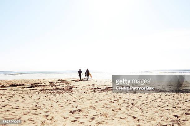 surf shop owners head boards in hand to the beach. - distant people stock pictures, royalty-free photos & images