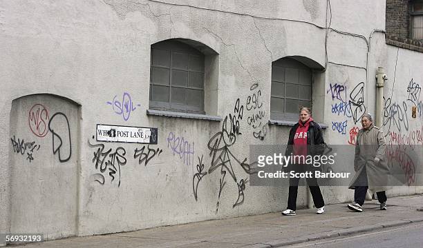 People walk past a wall adorned with graffiti near the site of the London 2012 Olympics in the East London borough of Stratford on February 24, 2006...
