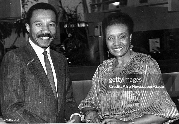 Kweisi Mfume, wearing a suit, sitting at a table with a woman, 1987.