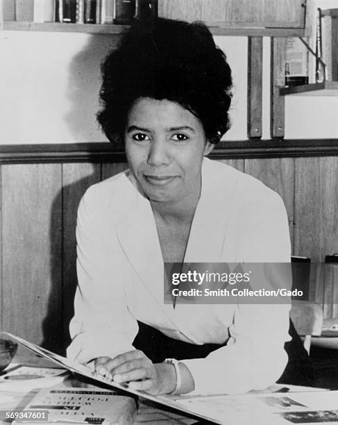 Lorraine Hansberry, sitting at a desk with books and papers, 1955.