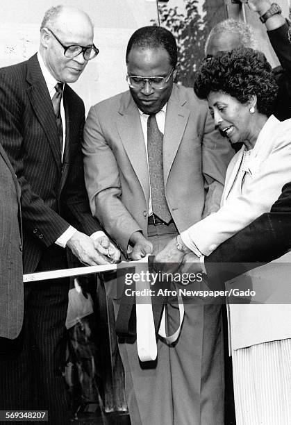 Mayor Kurt Schmoke and two other people cutting the ribbon to open the new National Fraternity House for Alpha Phi Alpha, 1980.