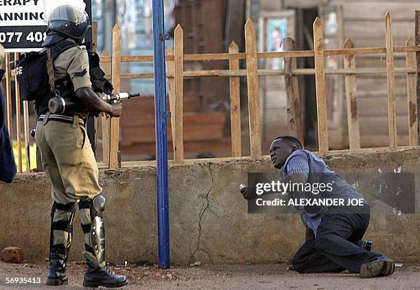 Ugandan opposition supporter pleads with a policeman 25 February 2006 after police fired live rounds and teargas at rock-throwing supporters of...