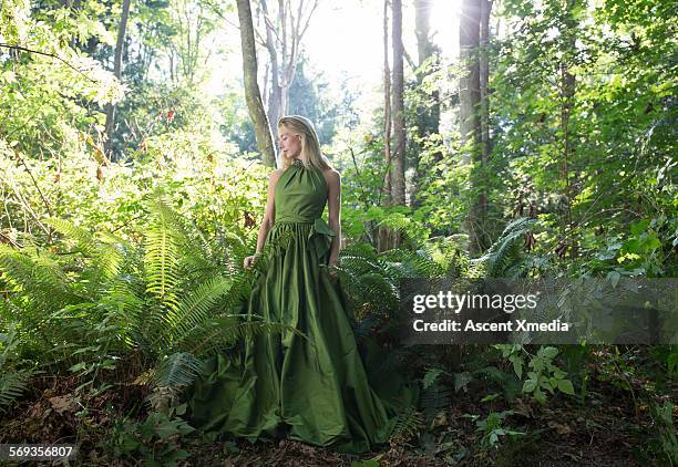 female model pauses in lush forest, contemplative - traje verde fotografías e imágenes de stock