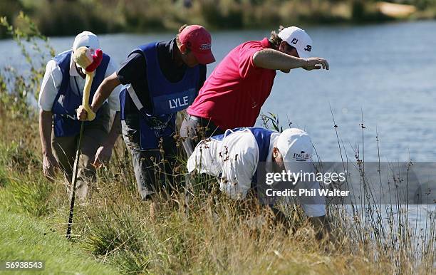 Jarrod Lyle of Australia looks for his ball on the edge of the lake after it landed in the water when he was tied for 1st place on the fourth day of...