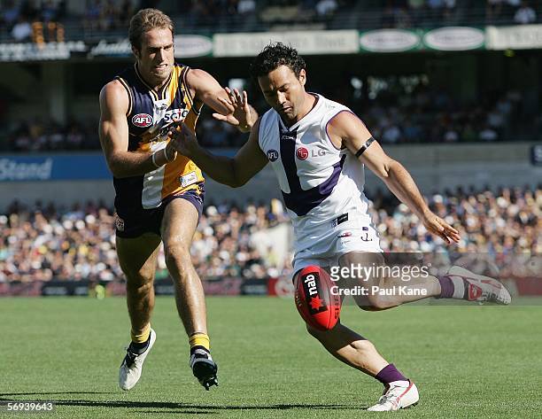 Peter Bell of the Dockers gets his kick away ahead of Chris Judd of the Eagles during the round one NAB Cup match between the West Coast Eagles and...