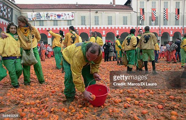 An orange thrower collects oranges as he awaits the next team of carriages to arrive during the battle of oranges on February 26, 2006 in Ivrea,...