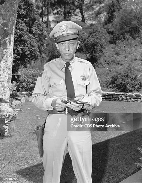 Publicity portrait of American actor Don Knotts who stands outdoors and holds his gun in the CBS rural sitcom 'The Andy Griffith Show,' July 30, 1962.