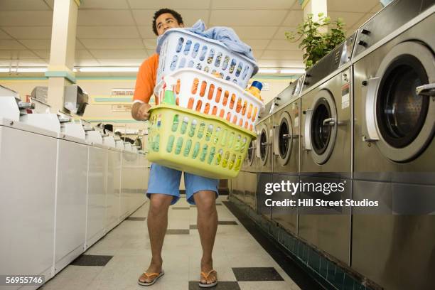 man carrying baskets of clothes in launderette - carrying laundry stock pictures, royalty-free photos & images