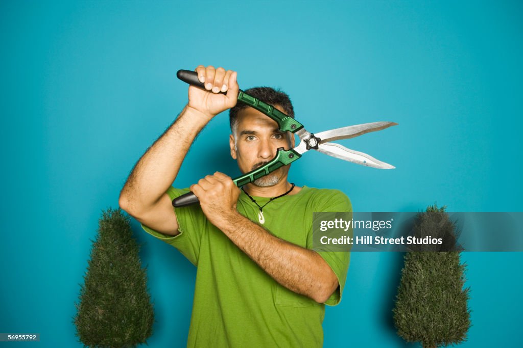 Portrait of man holding hedge clippers in front of face