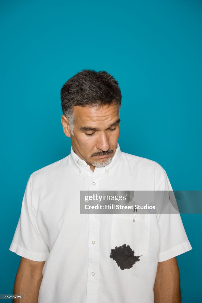 Man looking at ink stain on shirt