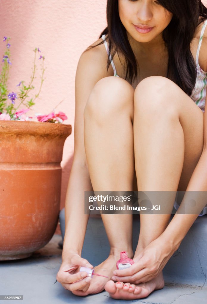 Woman sitting on stairs painting toenails