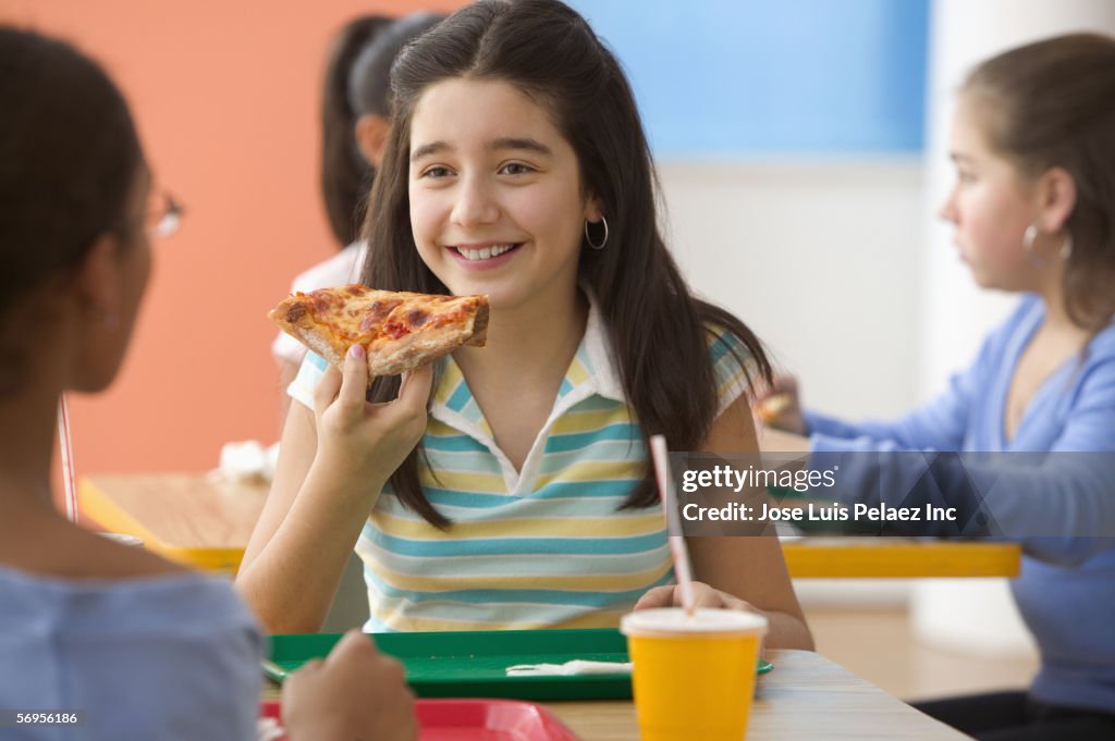 Four girls eating pizza in cafeteria